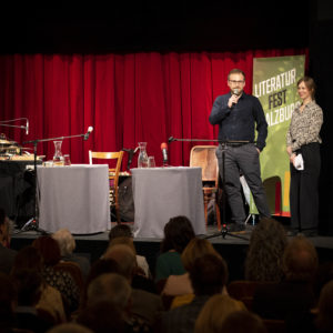 Kurator:innen Josef Kirchner und Anna Weidenholzer auf der Bühne bei der Eröffnung des 15. Literaturfest Salzburg