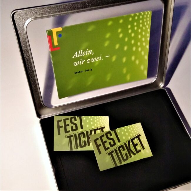 zwei Festtickets in Metallbox und mit Postkarte, auf der steht "Allein, wir zwei" von Stefan Zweig