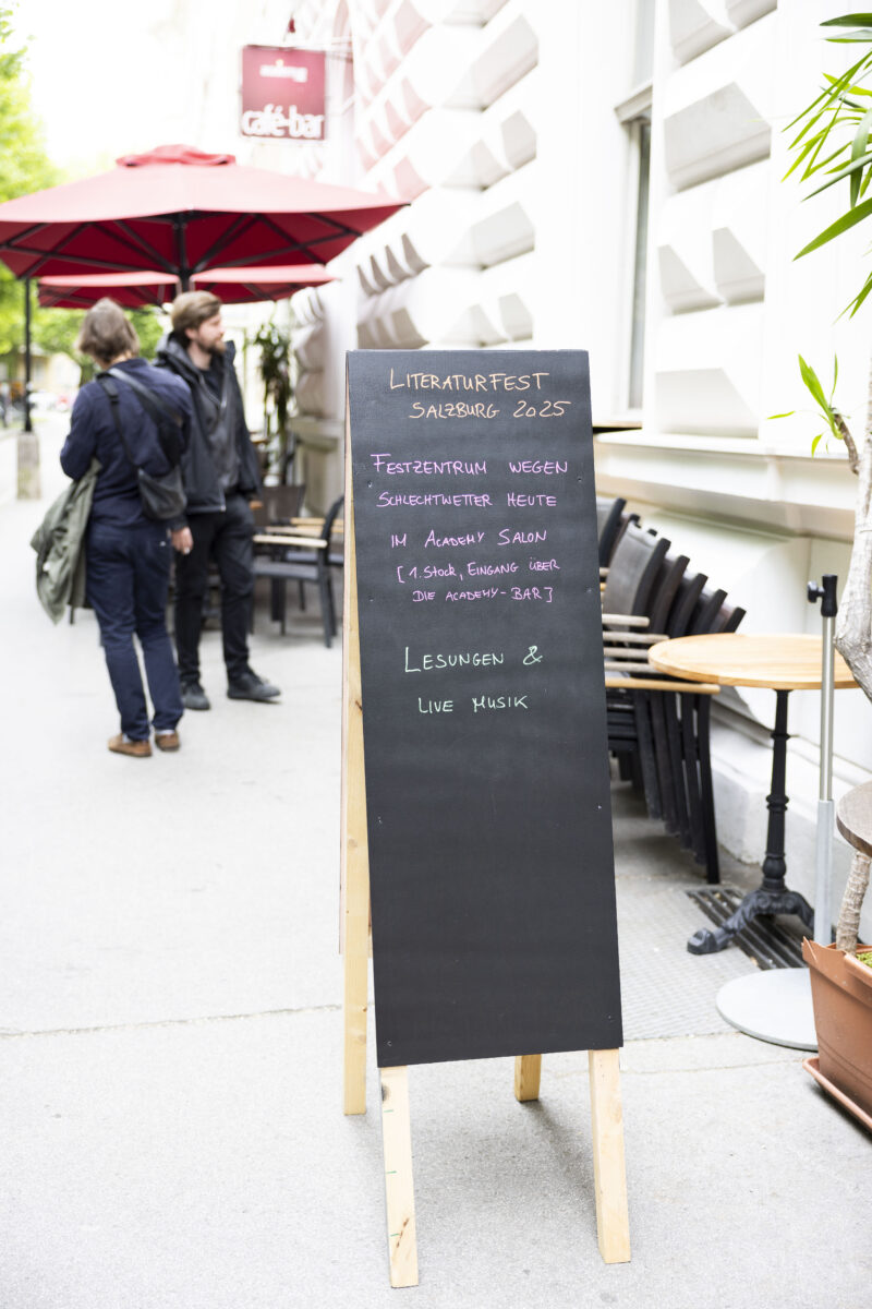 Schild vor dem Toihaus Theater, dass die Lesungen wegen Schlechtwetter in die Academy Bar verlegt wurden