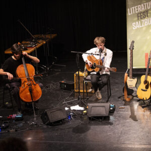 Musiker Lukas Lauermann am Cello und Doppelfinger an der Guitarre/Gesang